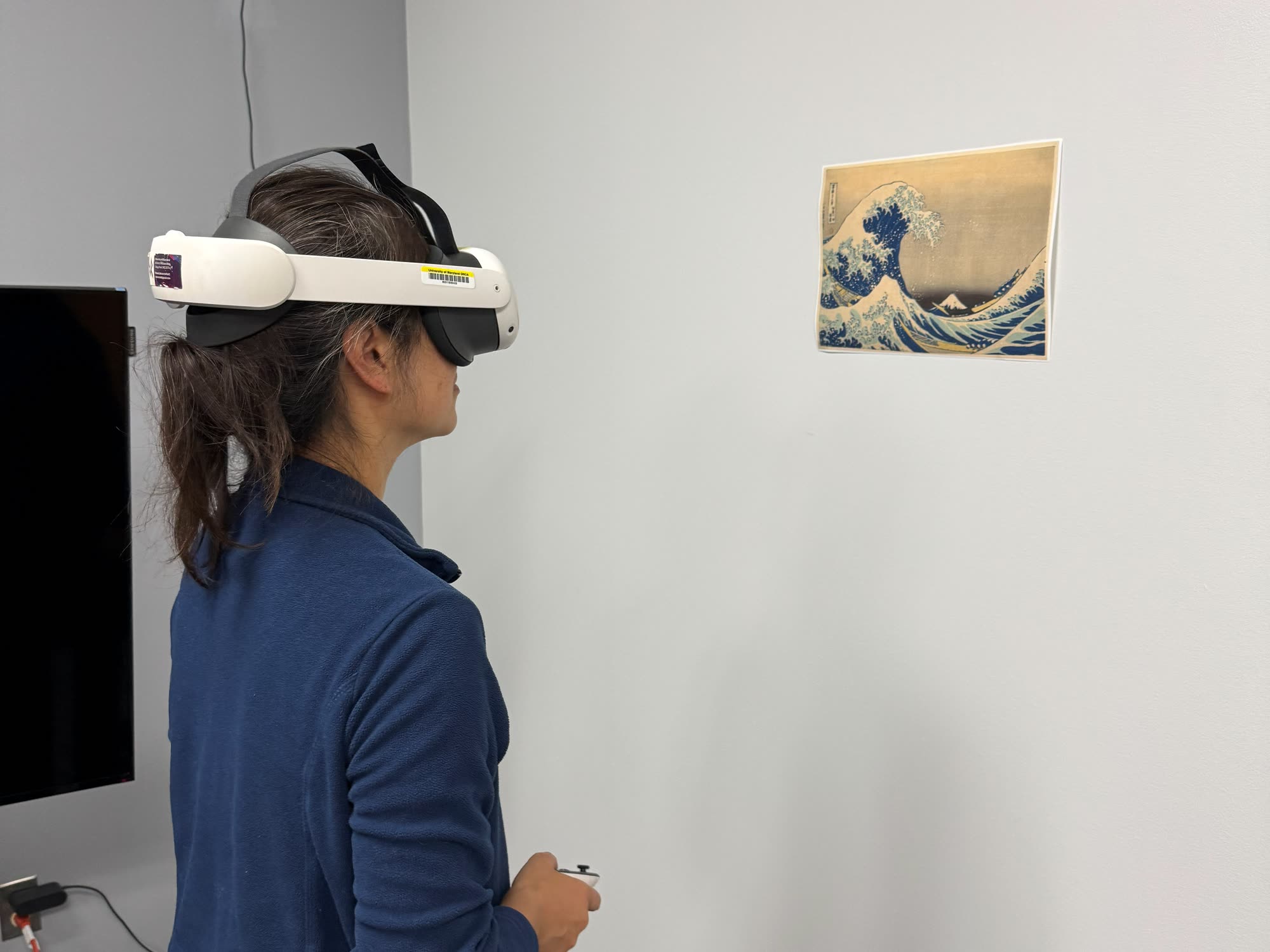 A tester in a Quest 3 headset looks at a print of The Great Wave taped to a wall.